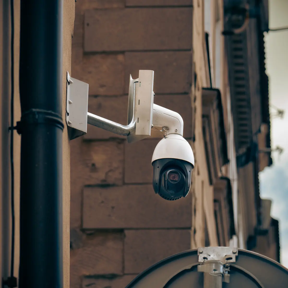 White PTZ dome CCTV camera mounted on the exterior wall of a building
