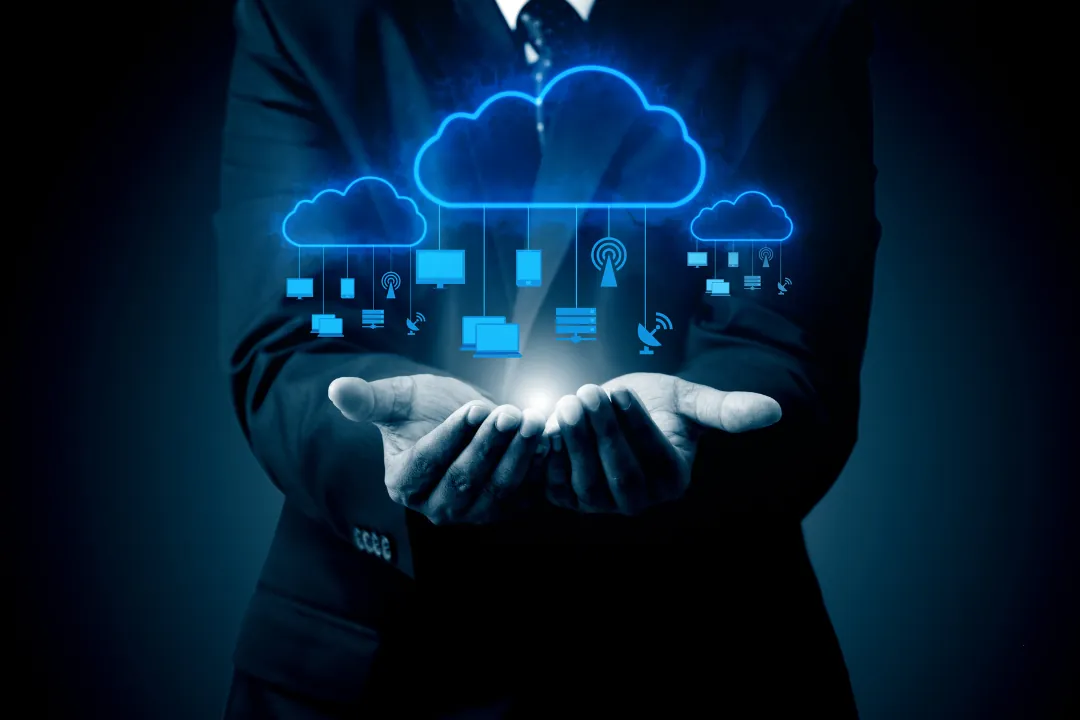 Hands holding cloud icons connected to devices, in blue light