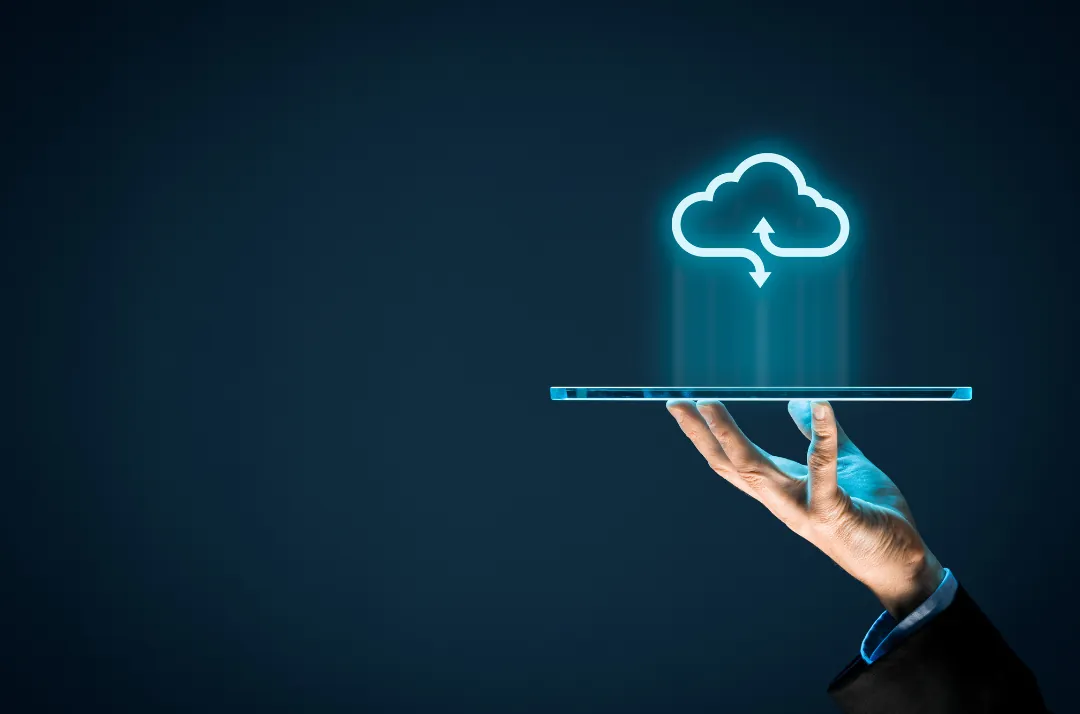 Hand holding a tablet with a cloud sync icon above it