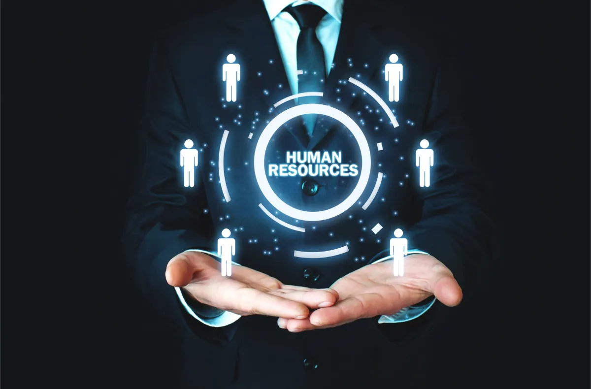 Hands presenting a glowing Human Resources icon with people around it