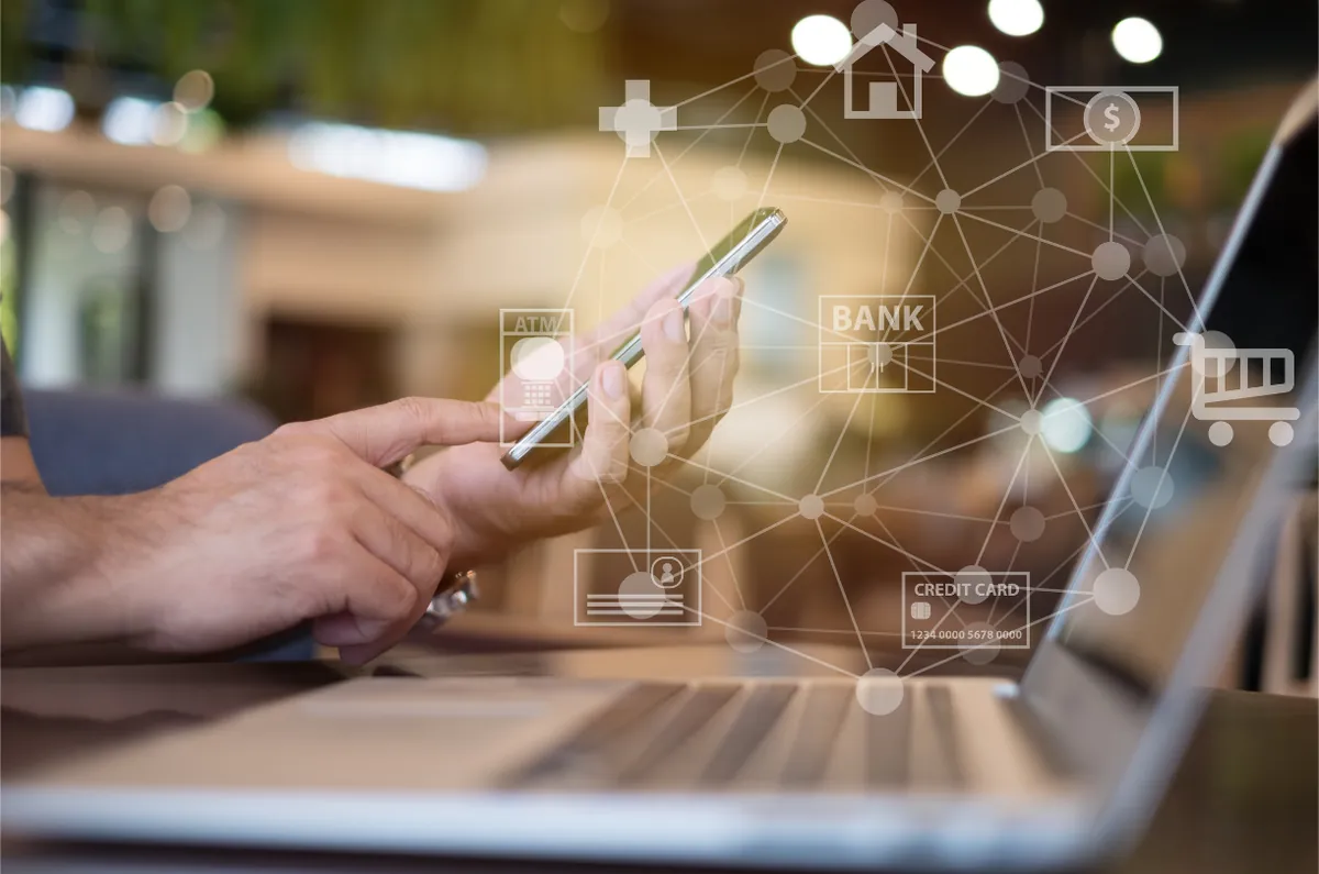 Hands using a smartphone and a laptop with connected service icons