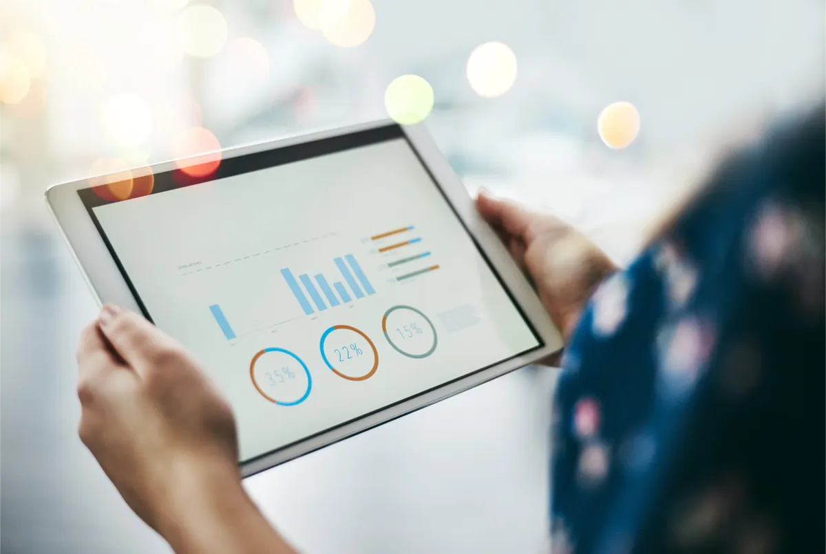 Hands holding a tablet showing analytics charts