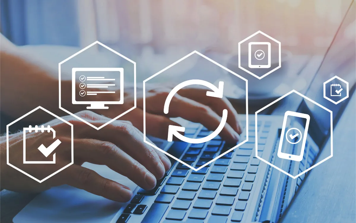 Hands typing on a laptop with workflow and sync icons